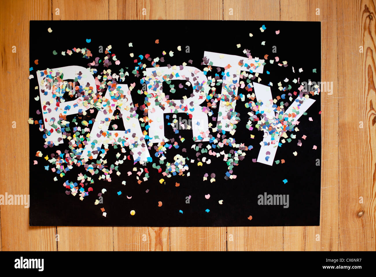 Konfetti und Buchstaben PARTY auf einem schwarzen Plakatkarton Stockfoto