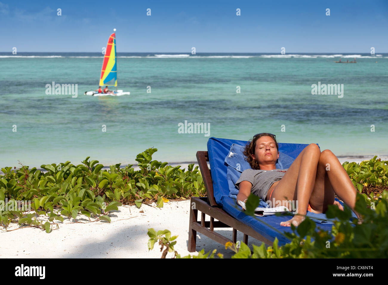 Eine Frau, Sonnenbaden am Strand, auf einem tropischen Urlaub Sansibar Afrika Stockfoto