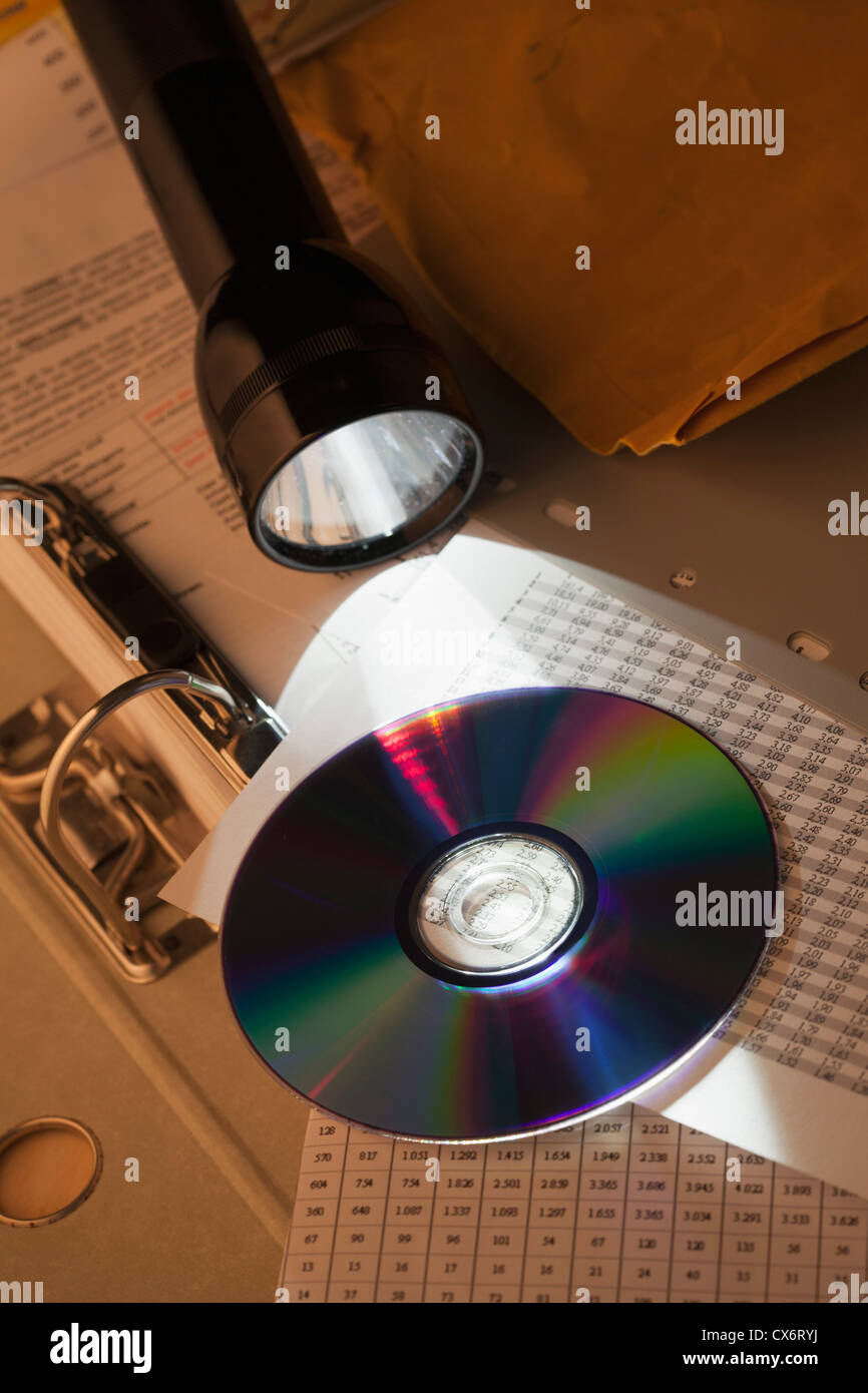 Eine Taschenlampe beleuchten einer CD-ROM auf einem Arbeitsblatt und binder Stockfoto
