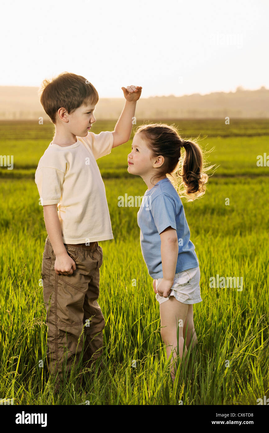 Ein Junge und ein Mädchen in einem Feld Vergleich Höhen Stockfoto