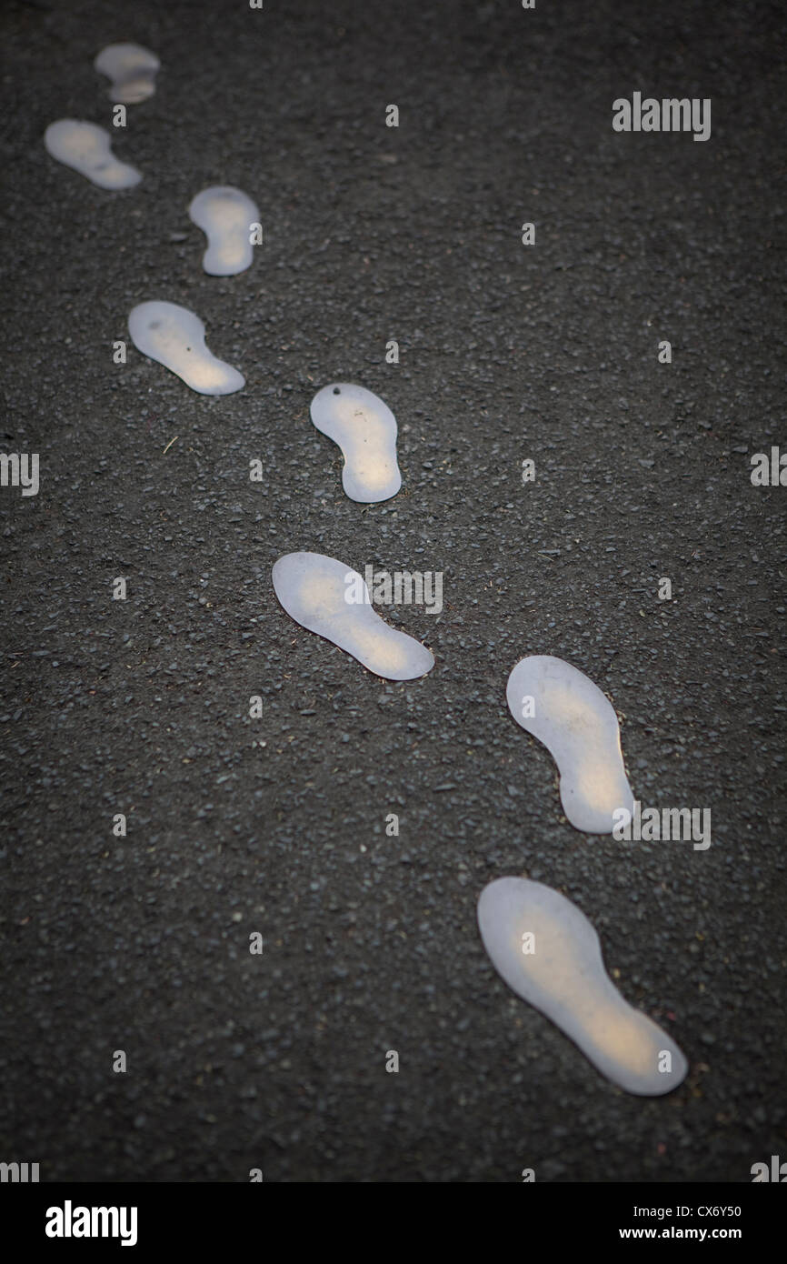 Einen weißen Fußabdruck Pfad auf einer schwarzen Straße. Stockfoto