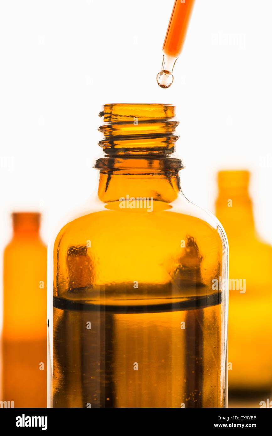 Pipette mit roten Substanz über transparente braune Flasche gehalten Stockfoto
