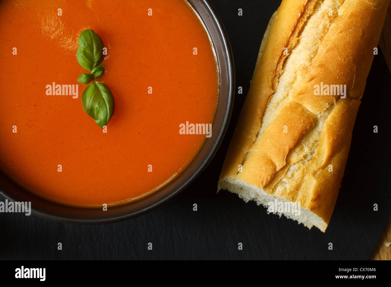 Schüssel mit Tomaten Suppe und Basilikum garniert mit Brot-baguette Stockfoto