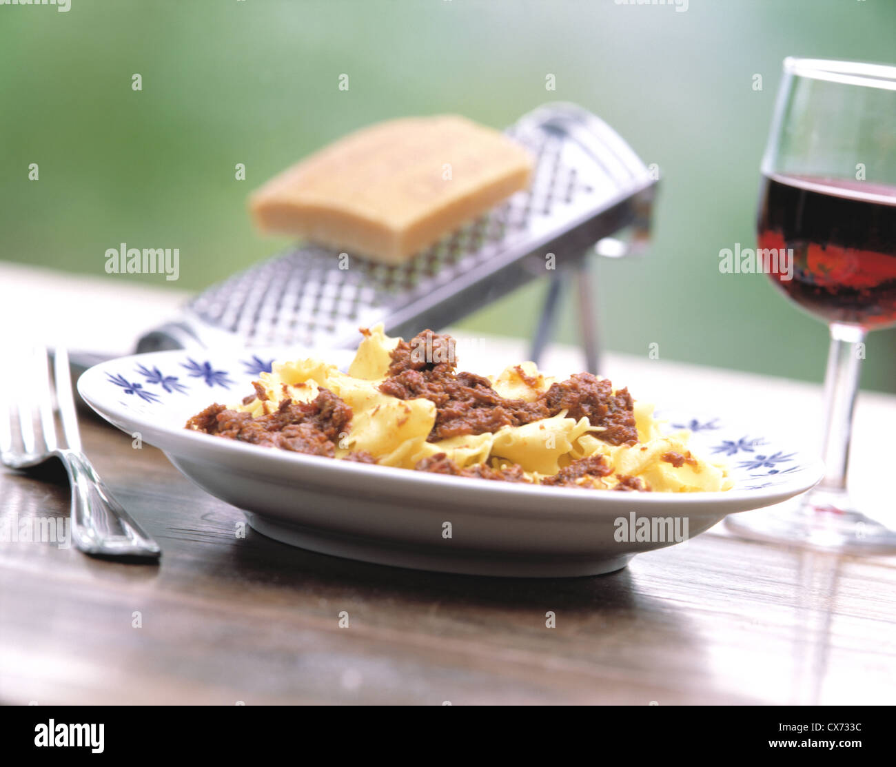 Noch Fattoria La Vialla: Pasta alle Ragout auf Holztisch mit Glas Rotwein und Parmesan mit Käse-Spachtel Stockfoto