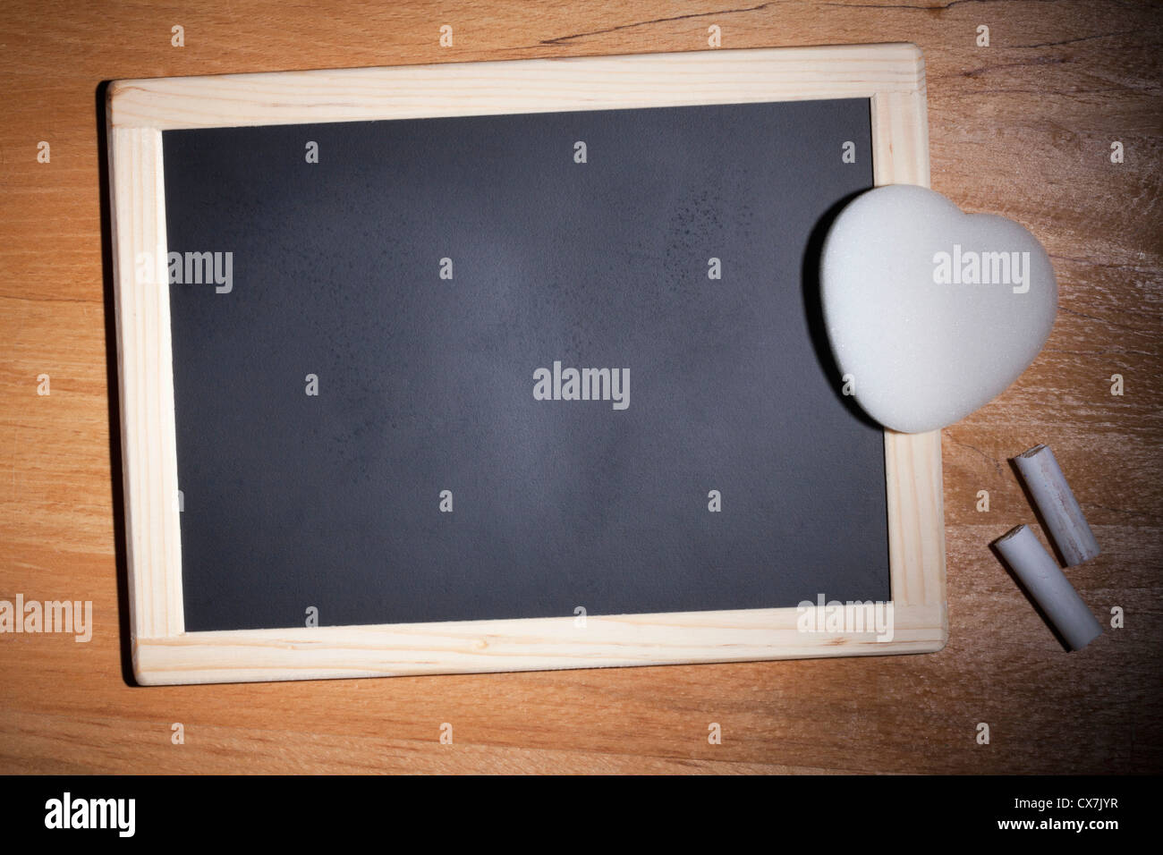 Eine kleine leere Tafel mit Kreide und ein Radiergummi in Herzform Stockfoto