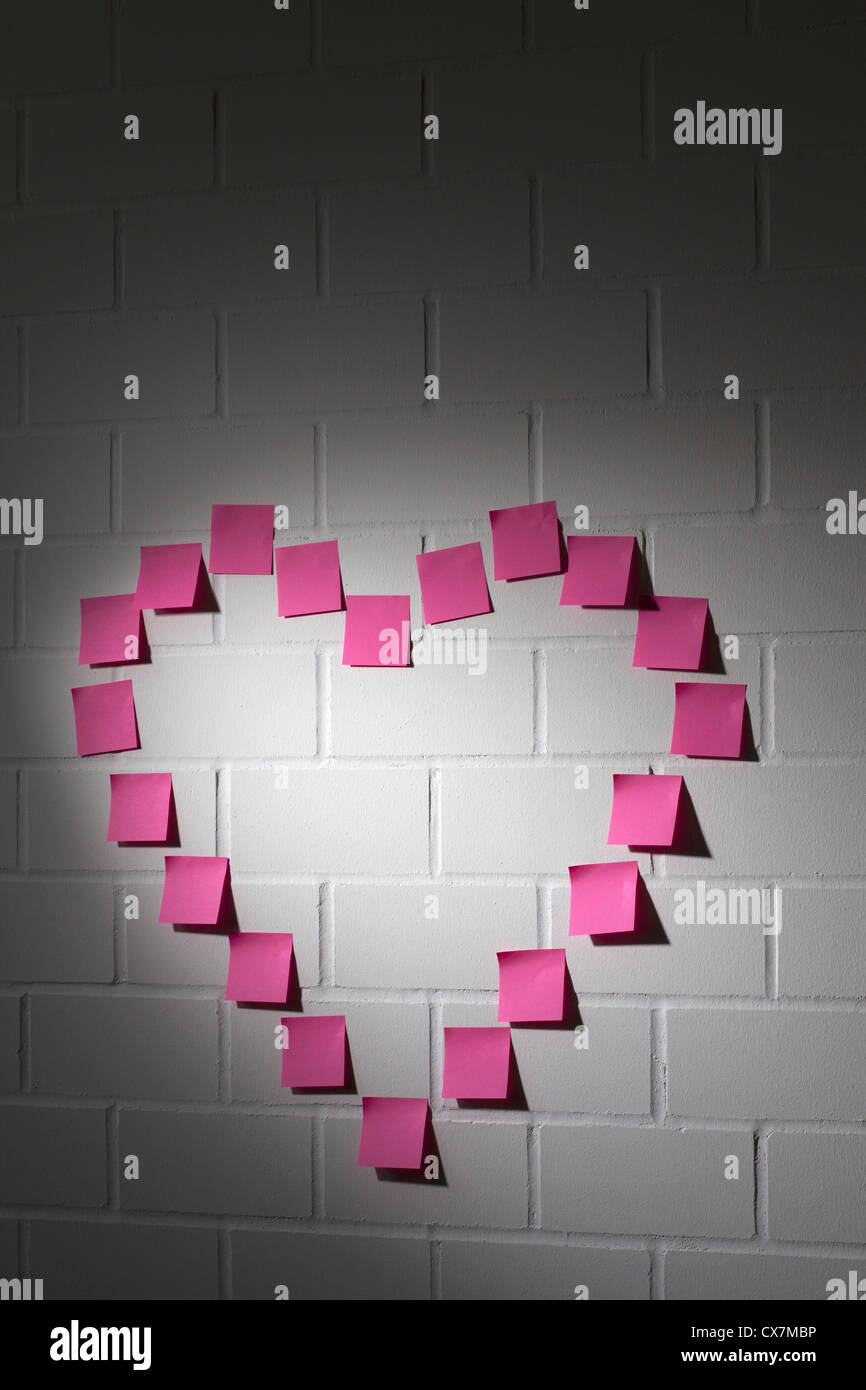 Leere Klebstoff Notizen in der Form eines Herzens auf eine Mauer angeordnet Stockfoto