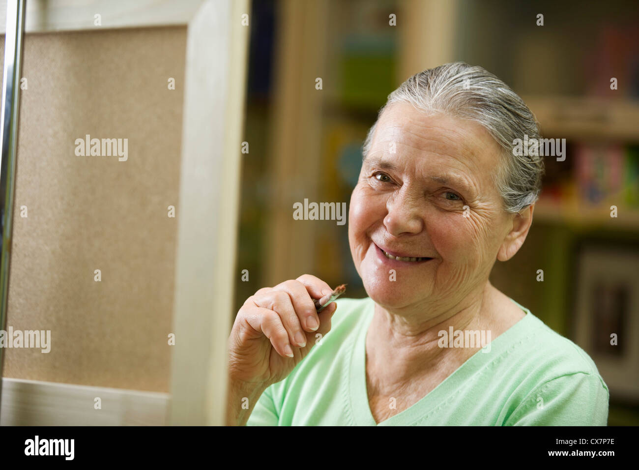 Eine fröhliche senior Frau hält einen Pinsel Stockfoto