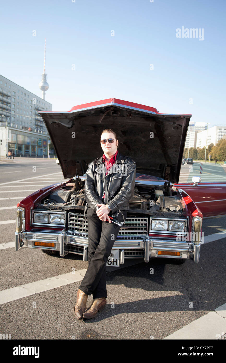 Eine coole Rockabilly-Mann hält lehnt sich an der Vorderseite des seinen Oldtimer, Haube, Werkzeuge Stockfoto