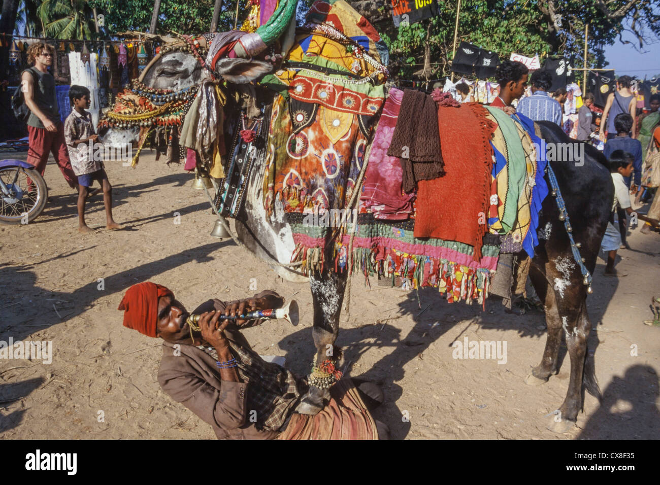 Hippie-Flohmarkt, indischen Jongleur Playng Querflöte mit Kuh, Anjuna Beach, Goa, Indien Stockfoto