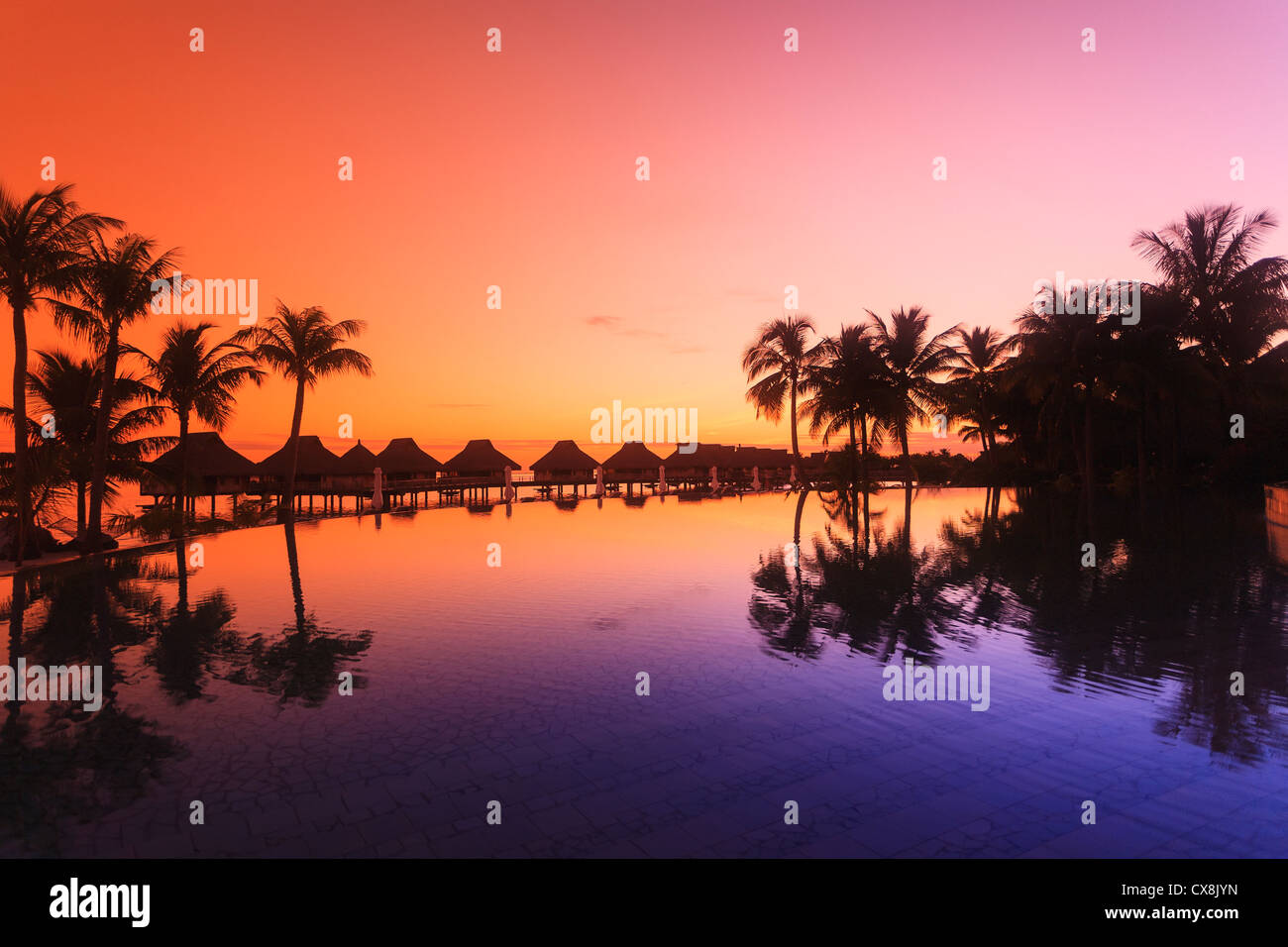 Sonnenuntergang und Palmen Bäume reflektiert in einem Pool im Bora Bora Nui Resort &amp; Spa; Insel Bora Bora, Französisch-Polynesien Stockfoto