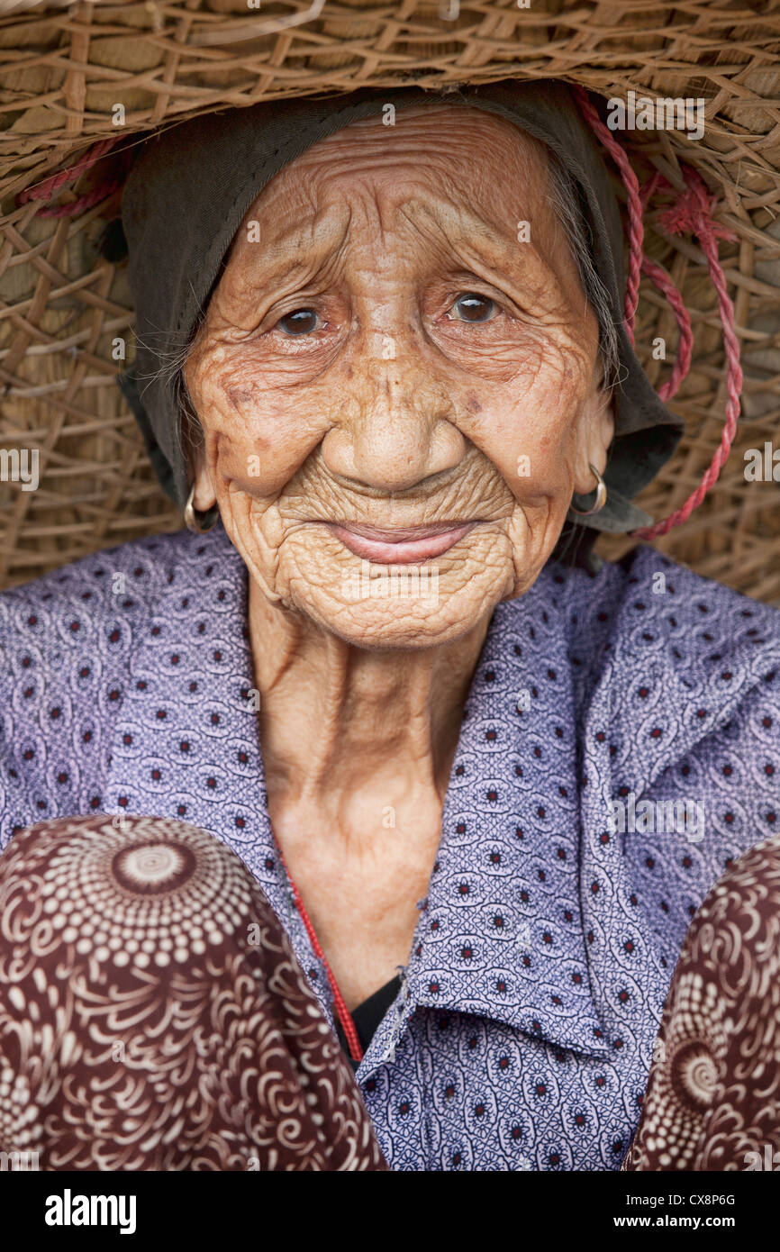 Eine schöne 93 Jahre alte Chinesin Ernte Reis die traditionelle Art und Weise mit ihren Händen den Toren Guilin, China Stockfoto