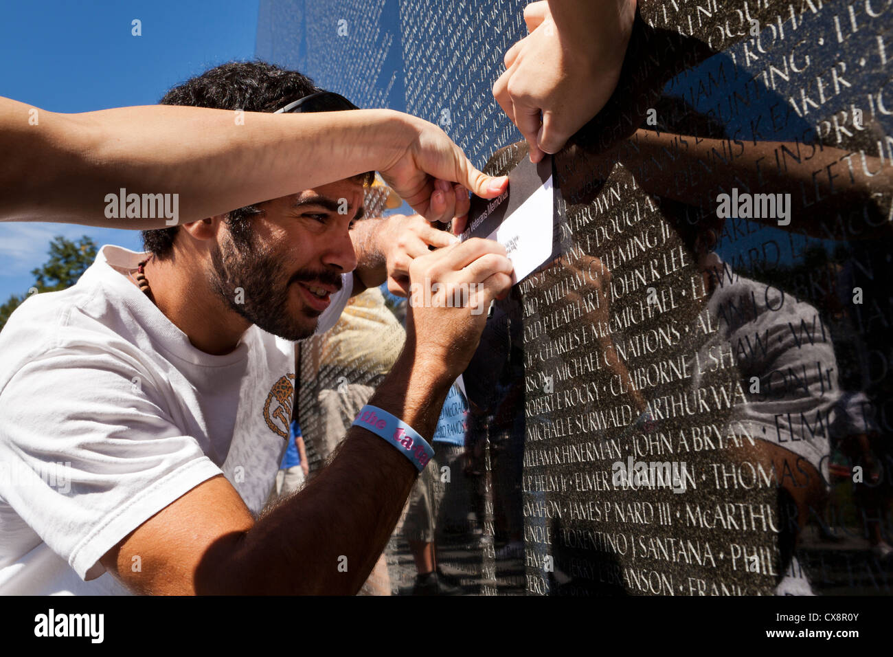 Junger Mann macht einen Bleistift Einreiben mit einen Namen an der Wand des Vietnam Veterans Memorial - Washington, DC USA Stockfoto