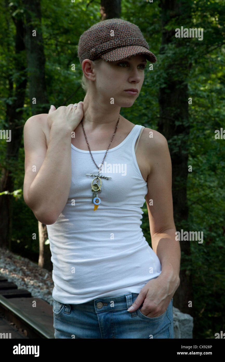 Cute blonde Frau in einem Unterhemd und kleine Kappe auf dem Kopf, außen in einigen Wäldern suchen nachdenklich Stockfoto
