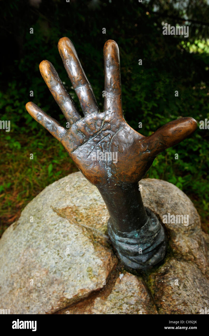 "Holt mich hier raus!" Skulptur von eine Hand greift aus einem Felsen bei Davos, Schweiz Stockfoto