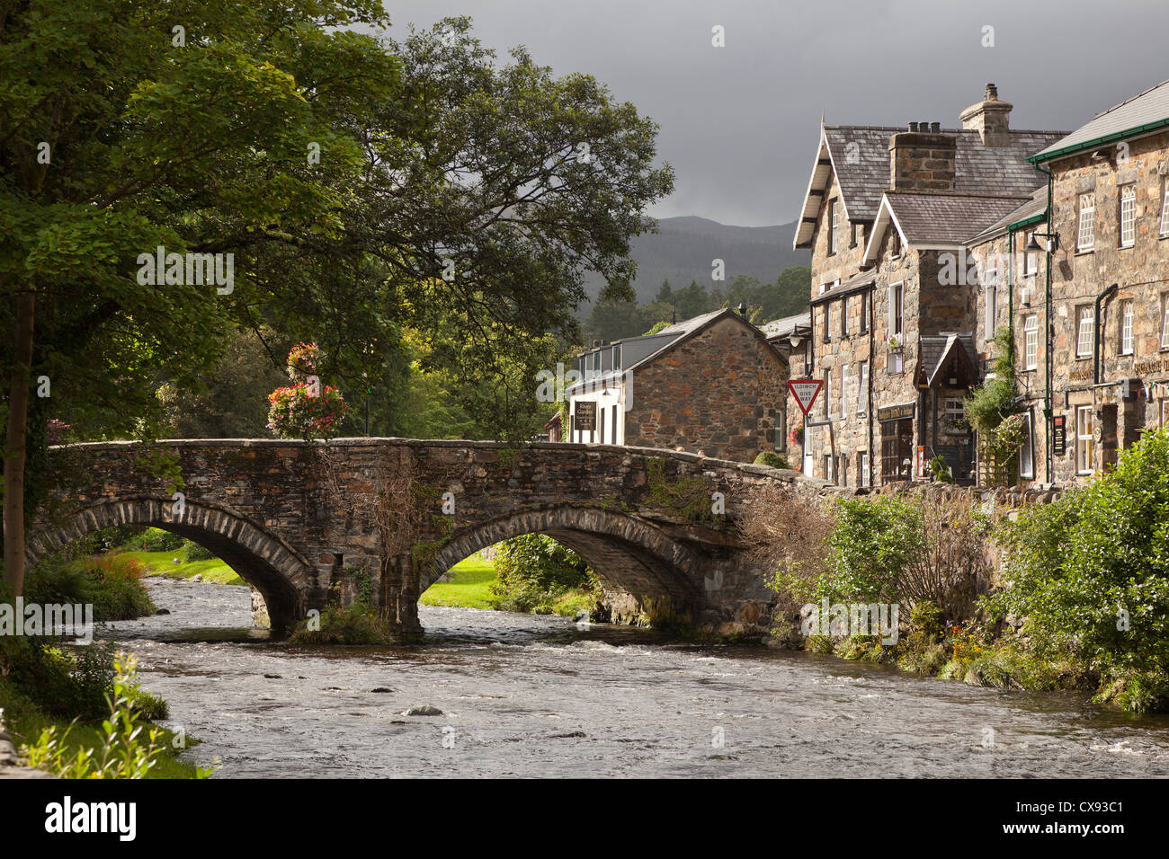 Eine alte Steinbrücke mit zwei Bögen in Beddgelert Dorfzentrum, Wales. Stockfoto