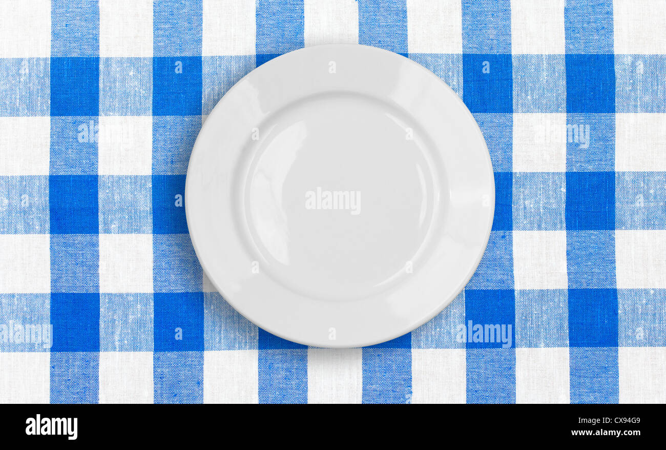 weißen Teller auf blauem aufgegebenen Stoff Tischdecke Stockfoto