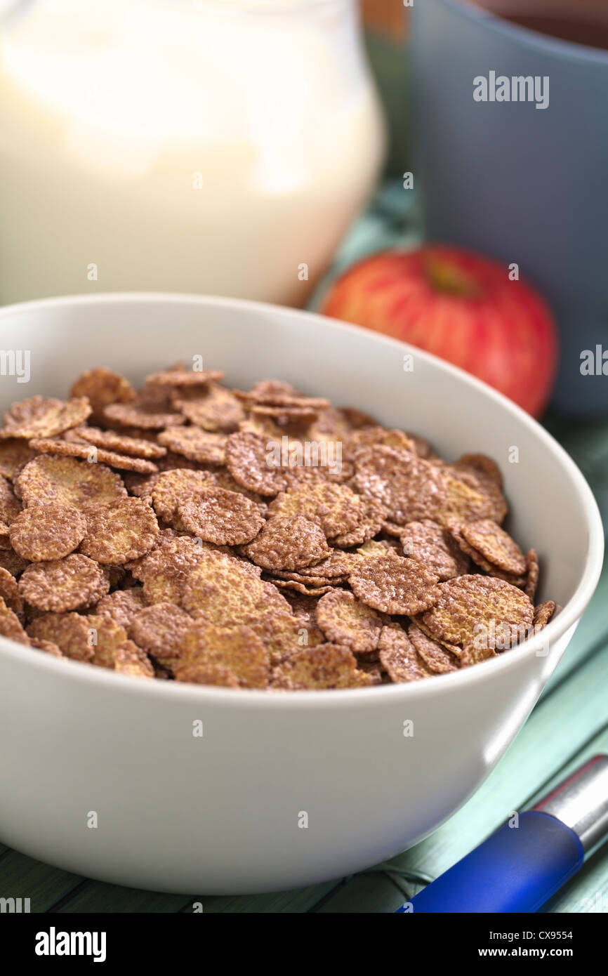 Schüssel Schoko Cornflakes Müsli mit Apfel, Tasse Kaffee/Tee und einen Krug Milch in den Rücken Stockfoto