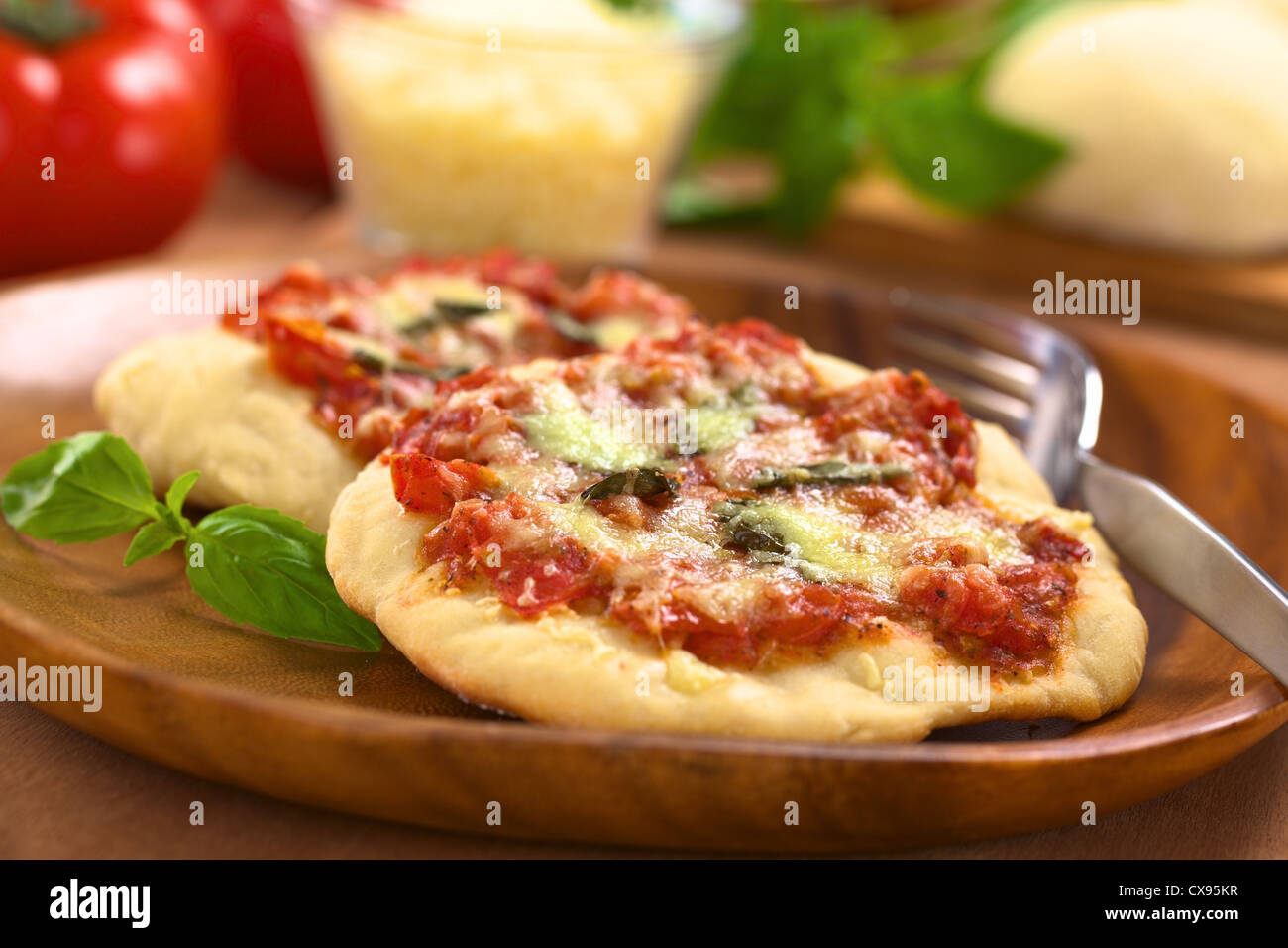 Knusprige hausgemachte Pizza Margherita oder Pizza Mozzarella (Pizza mit Tomaten, Basilikum und Käse) mit Gabel auf Holzplatte Stockfoto