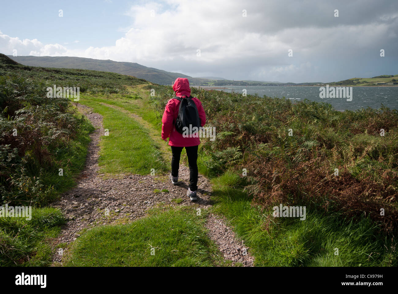 Rückansicht einer Frau Person zu Fuß durch die Landschaft tragen wasserdichte Kleidung und Rucksack Stockfoto