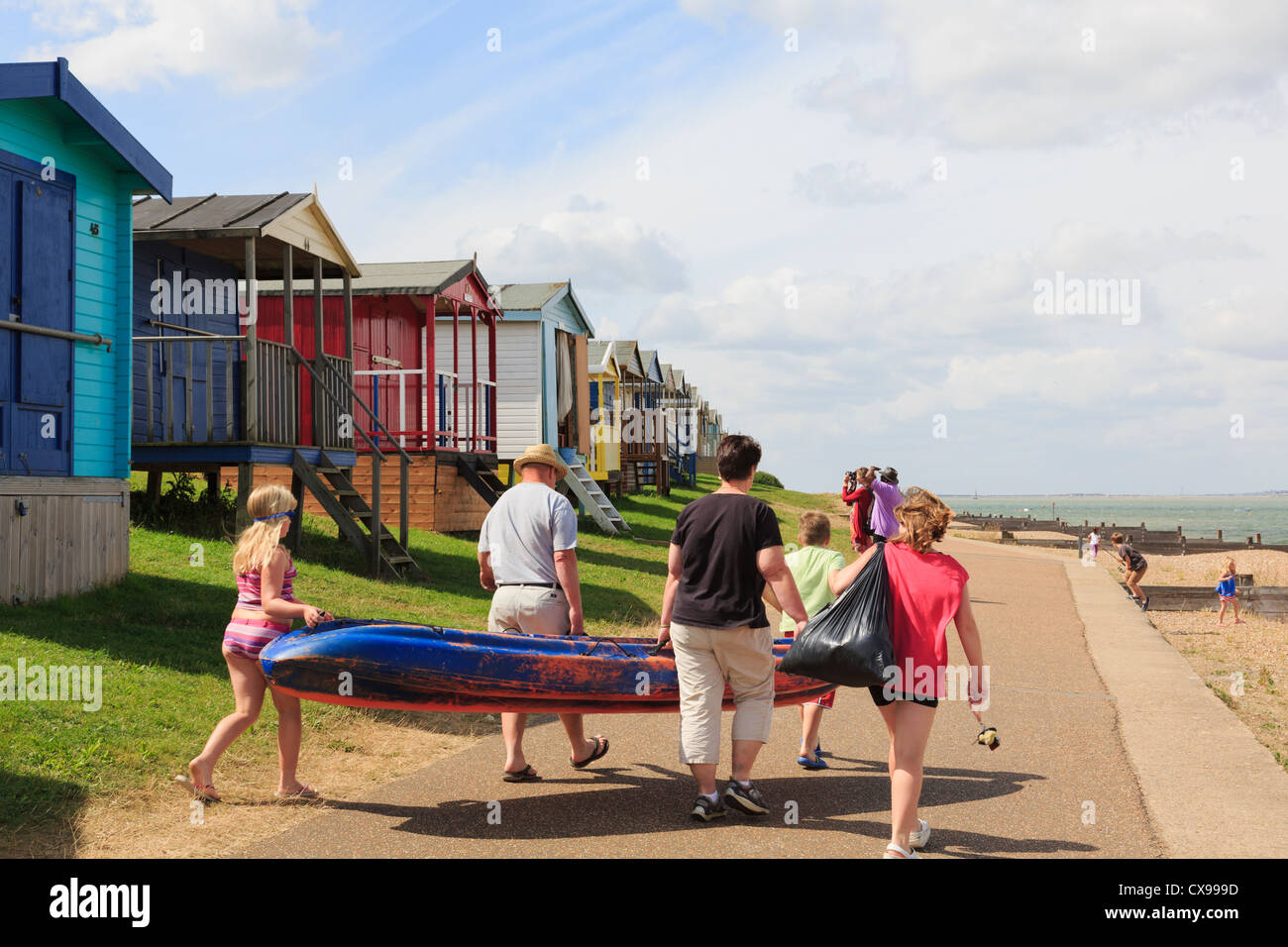Menschen auf Whitstable Strandpromenade mit Strandhütten auf North Kent Küste Thames Estuary im Sommer. Tankerton Whitstable Kent England Großbritannien Großbritannien Stockfoto