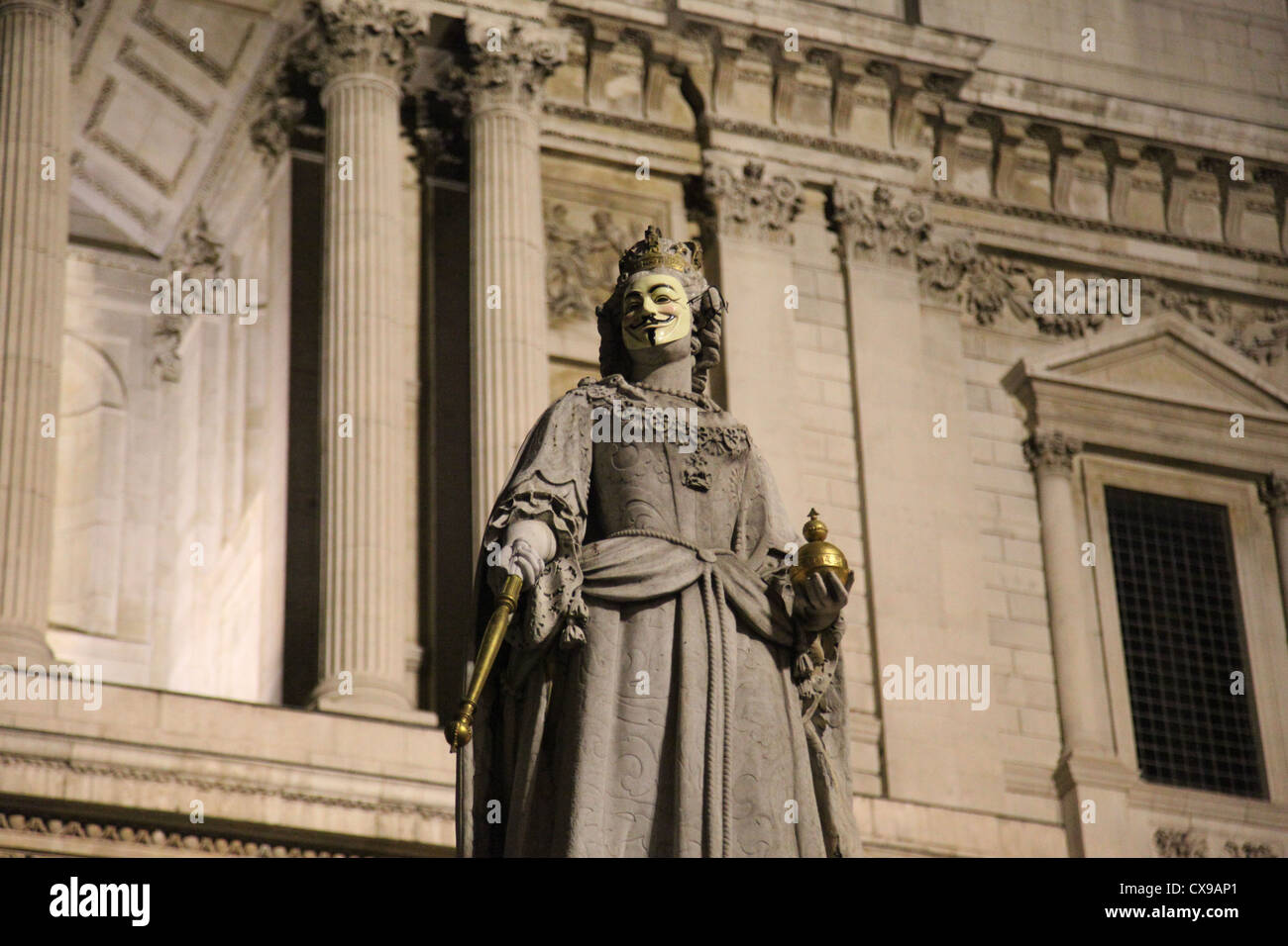 Eine anonyme Maske legt über das Gesicht der Queen Anne Statue außerhalb von St. Pauls Cathedral London. Stockfoto