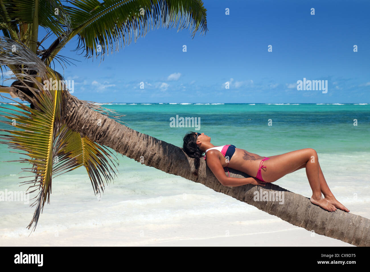 Eine junge Frau, Sonnenbaden auf einer Palme an einem tropischen Strand, Bjewuu, Sansibar Afrika Stockfoto