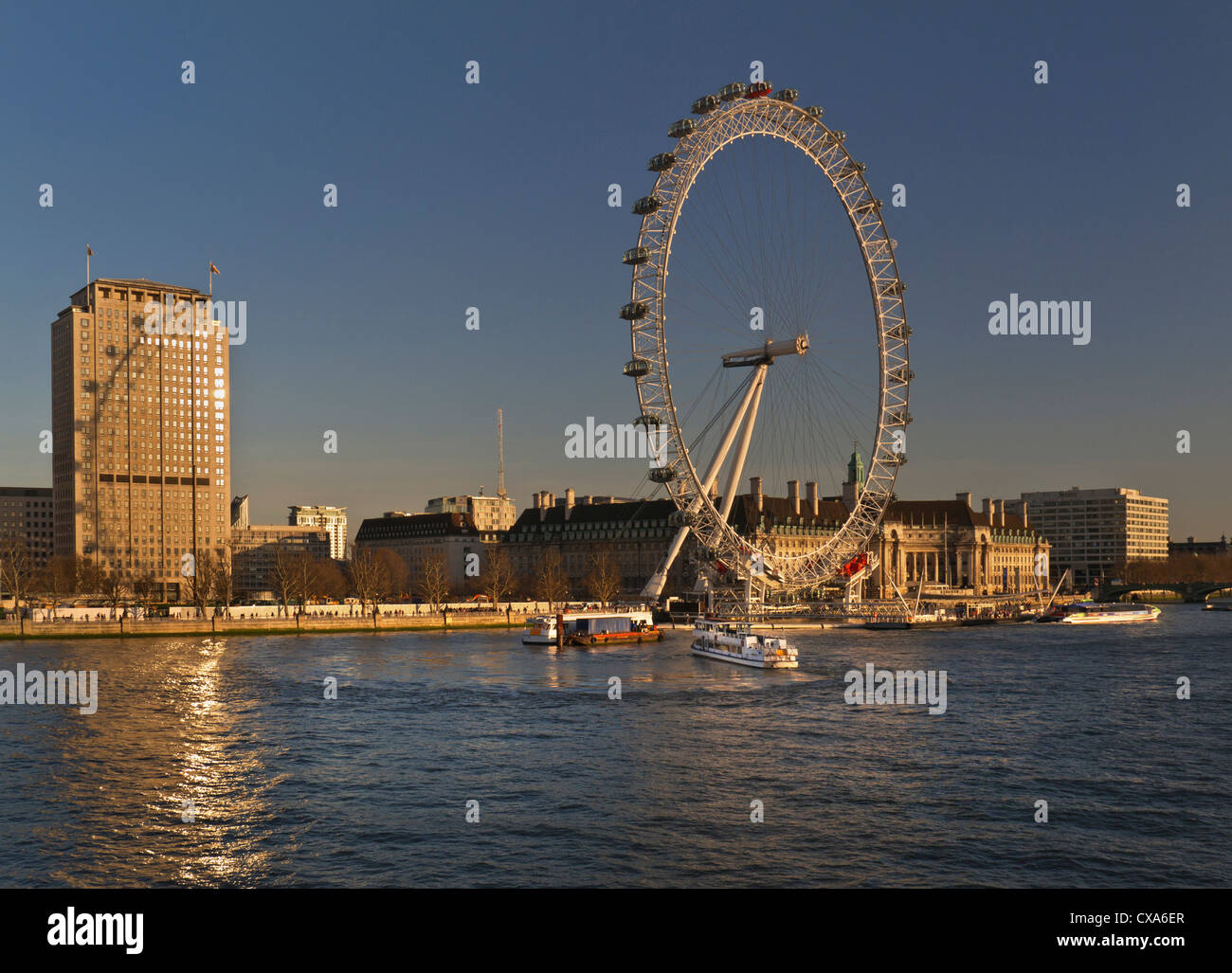 Das London Eye und Shell HQ beleuchtet durch Festlegen der Sonne Themse mit Tour Boot Liegeplatz neben South Bank London UK Stockfoto