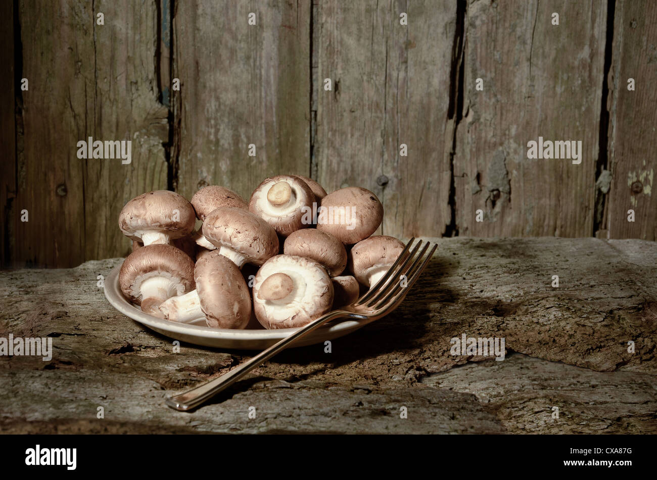 Bio Pilze produzieren braune Champignons roh in einem Teller bereit mit Gabel bereit, alte Tisch gegessen Nahrung gekocht werden abgeholt Stockfoto