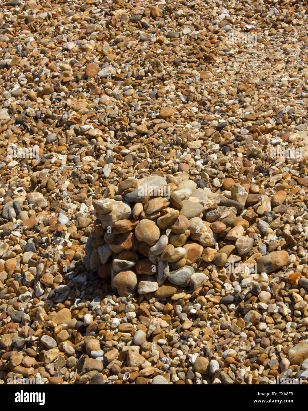 Haufen von Steinen am Strand von anderen Steinen erzeugen eine optische Illusion umgeben Stockfoto