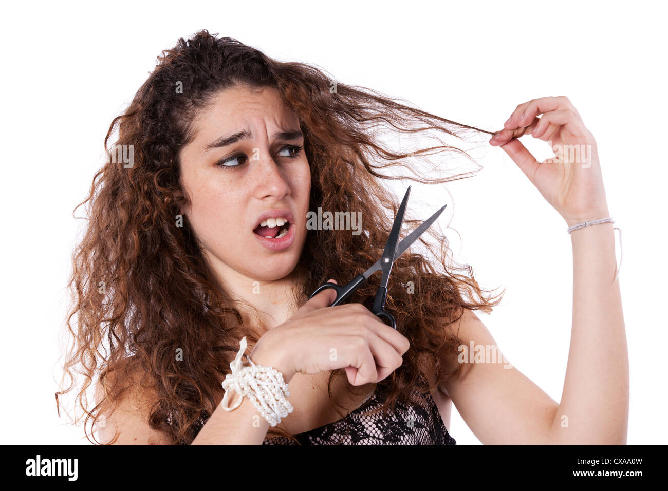 Unglückliche Frau, die ihre Haare mit einer Schere schneiden Stockfoto