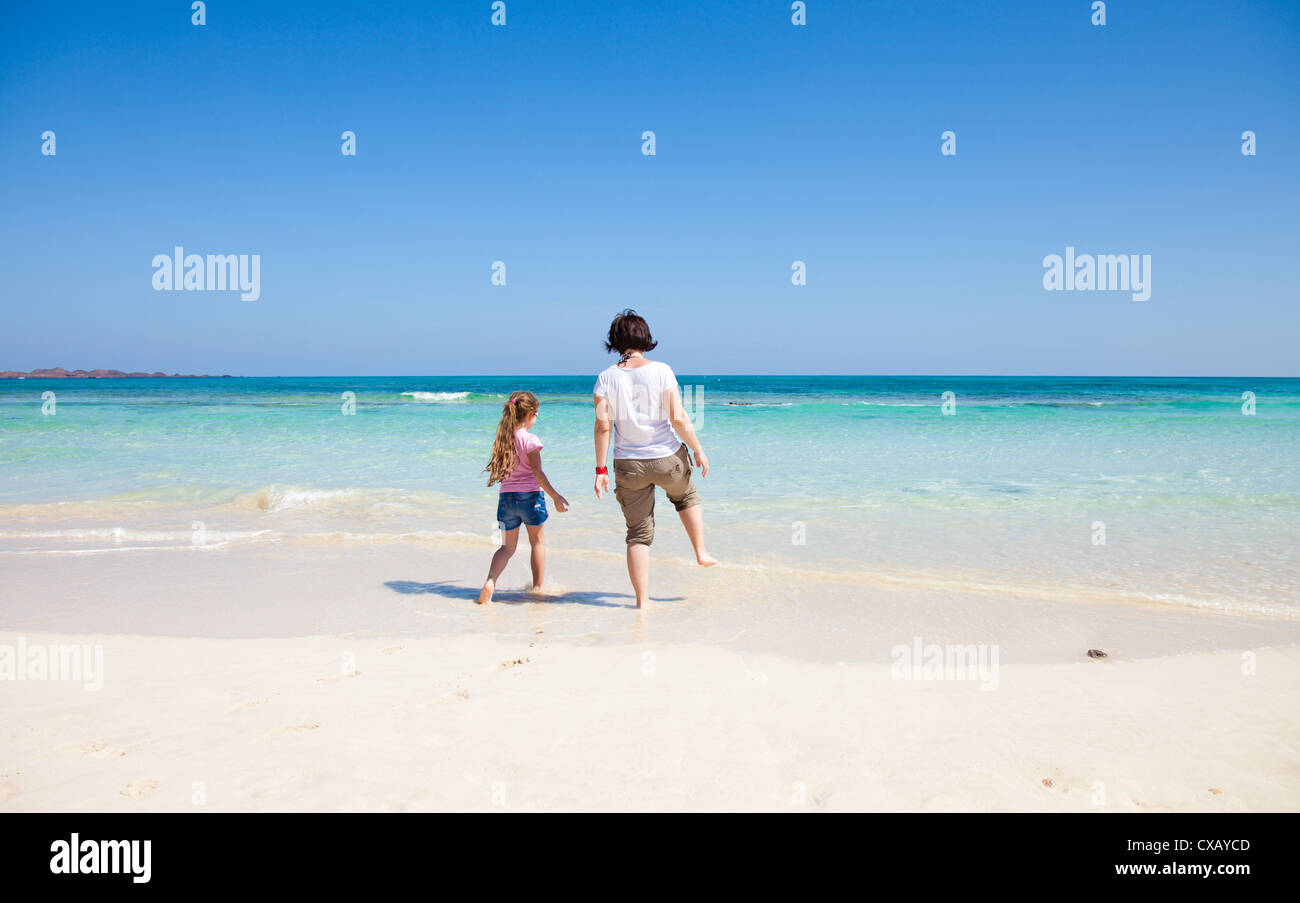 Mutter und Tochter spielen am Rand des Ozeans Stockfoto