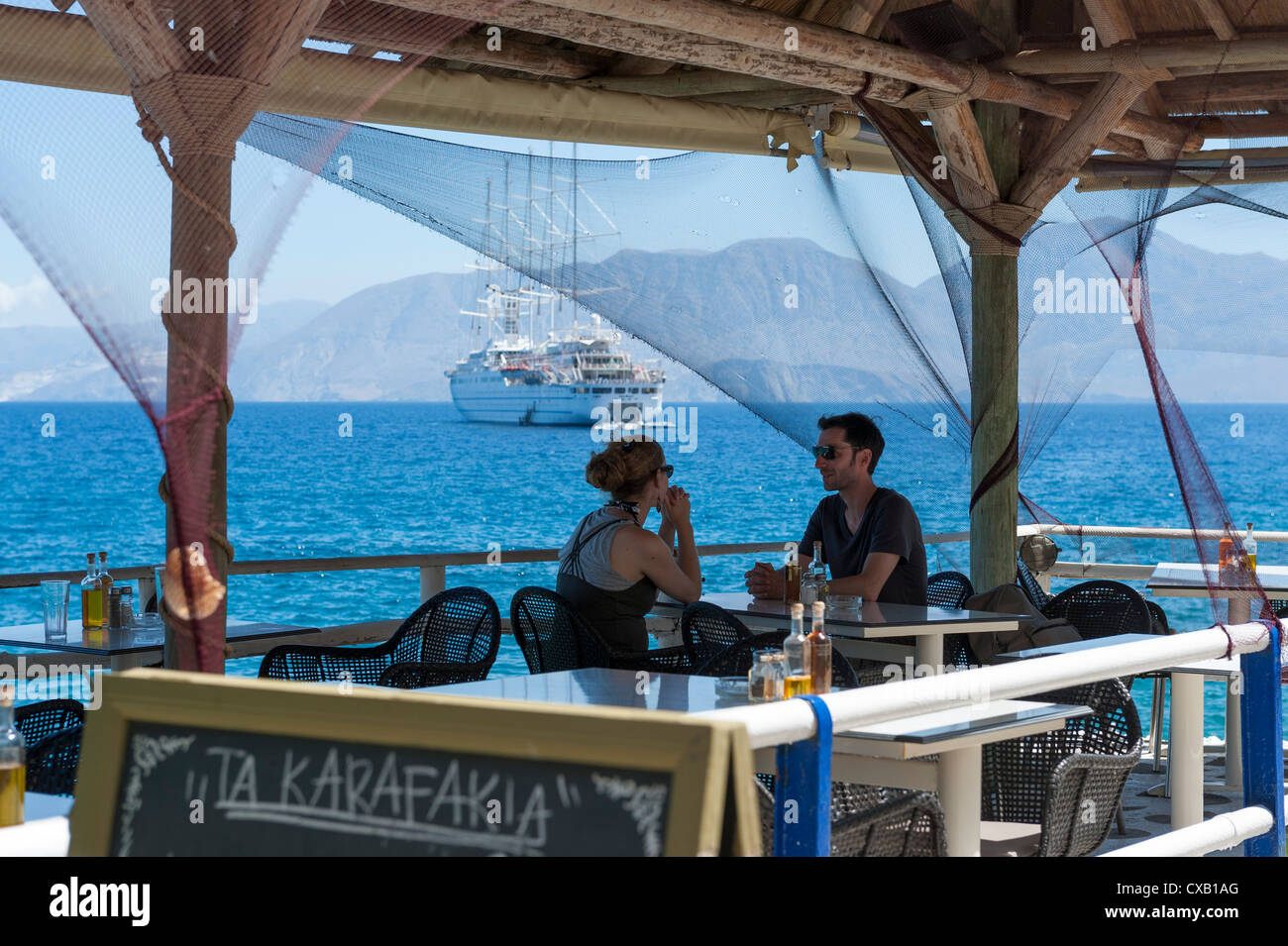 Ein paar in einer Taverne am Meer Agios Nikolaos Kreta mit dem Schiff Club Med zwei im Hintergrund Stockfoto
