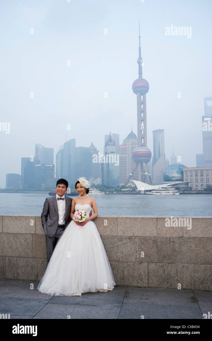 Jung verheiratet Paar posieren für Hochzeitsfotos am Bund mit Skyline von Pudong Finanzviertel hinten Shanghai China Stockfoto