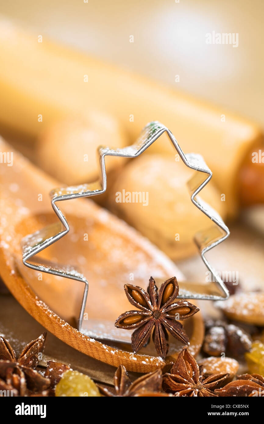 Weihnachten backen. Baum geformt Ausstecher mit Sternanis auf Holzlöffel umgeben von Rosinen, Mandeln und Nüssen Stockfoto