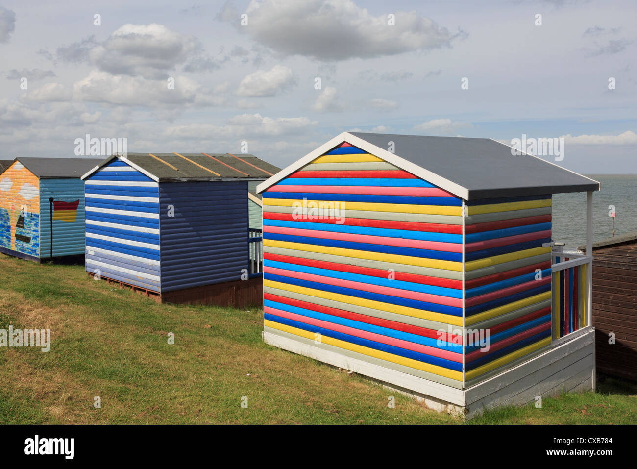 Bunte hölzerne Strandhütten mit Blick auf die Themse-Mündung im Norden Kent Küste bei Tankerton Whitstable Kent England UK Stockfoto