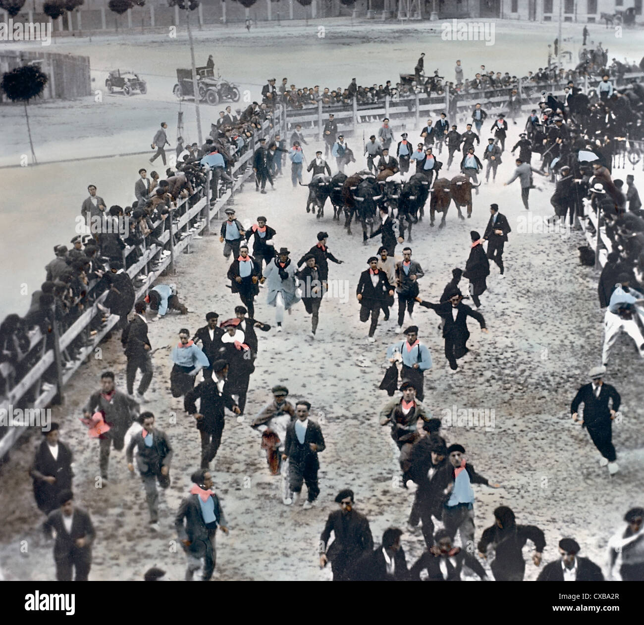 Eingefärbte, hochwinkelige Ansicht von Männern, die versuchen, einer Gruppe von aufladendem Bullen während des jährlichen Bullenlaufes auszuweichen, das während des Festivals von San Fermin, Pamplona, Spanien, Juli 1928 stattfindet. (Foto von Burton Holmes) Stockfoto