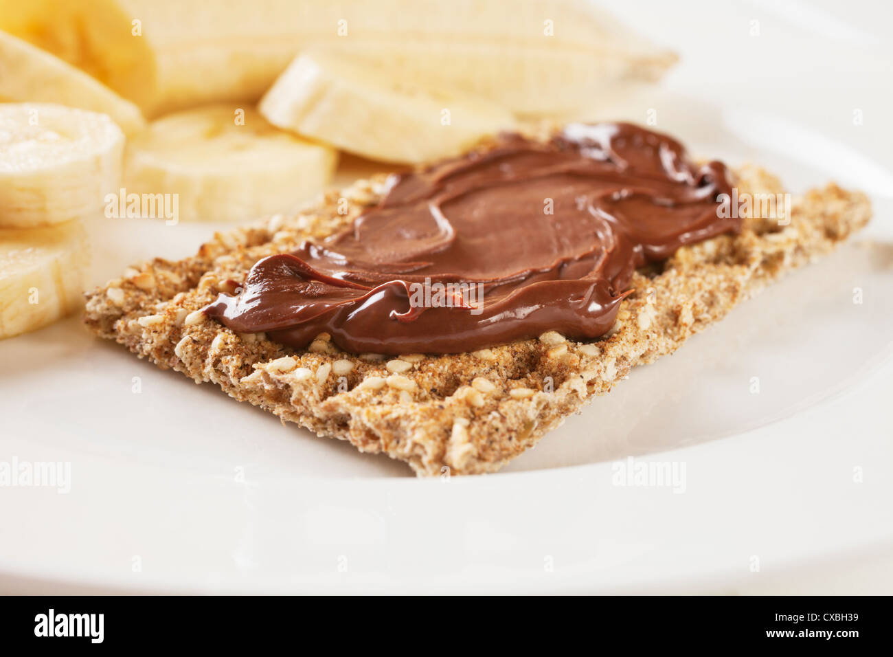 Eine kleine Mahlzeit von Knäckebrot mit Nutella und eine große Banane, für eine Gesamtmenge von 260 Kalorien oder 1100 Kilojoule. Stockfoto