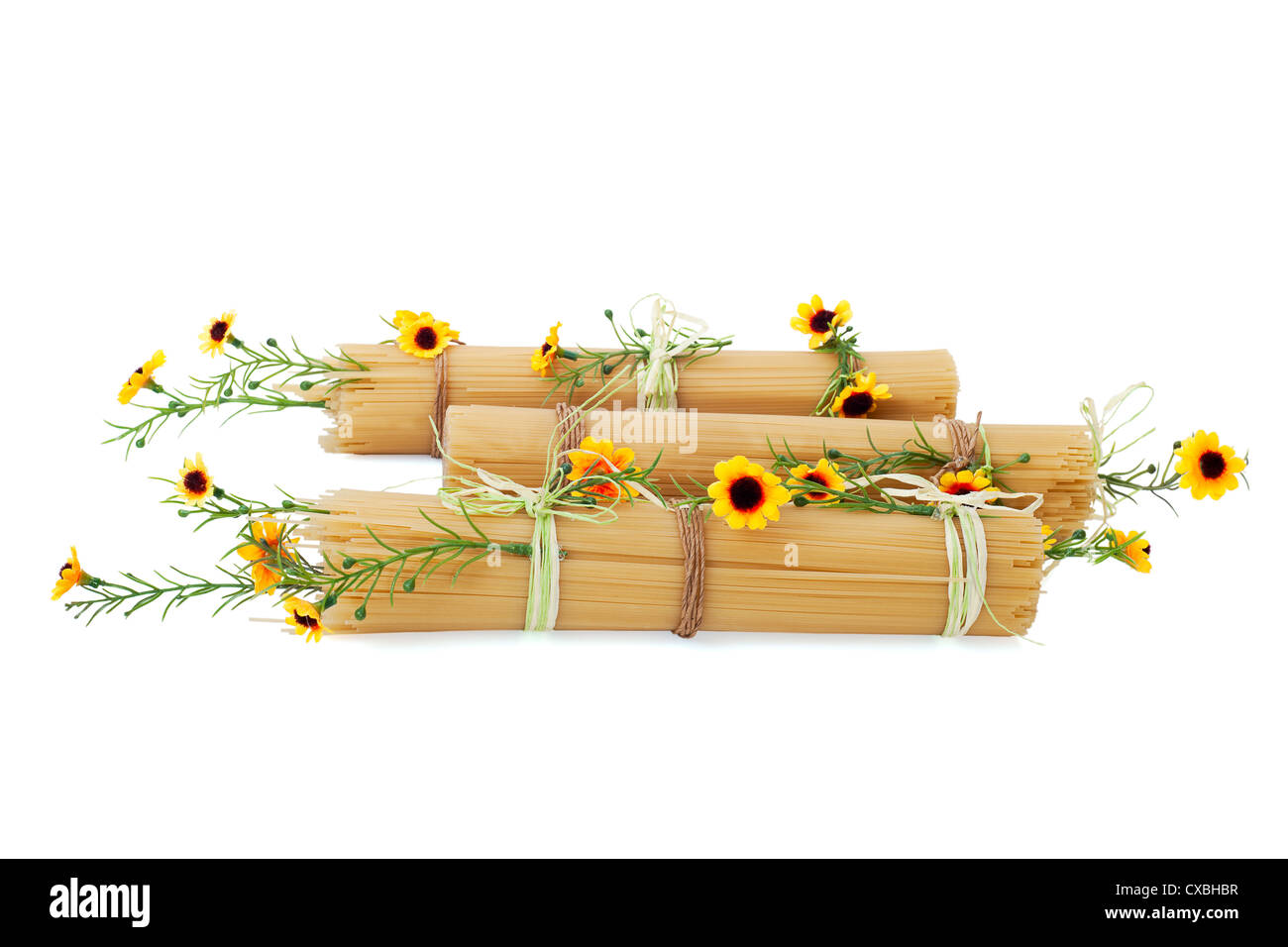 Ungekocht italienische Spaghetti, dekoriert mit gelben Blüten, die isoliert auf weißem Hintergrund Stockfoto