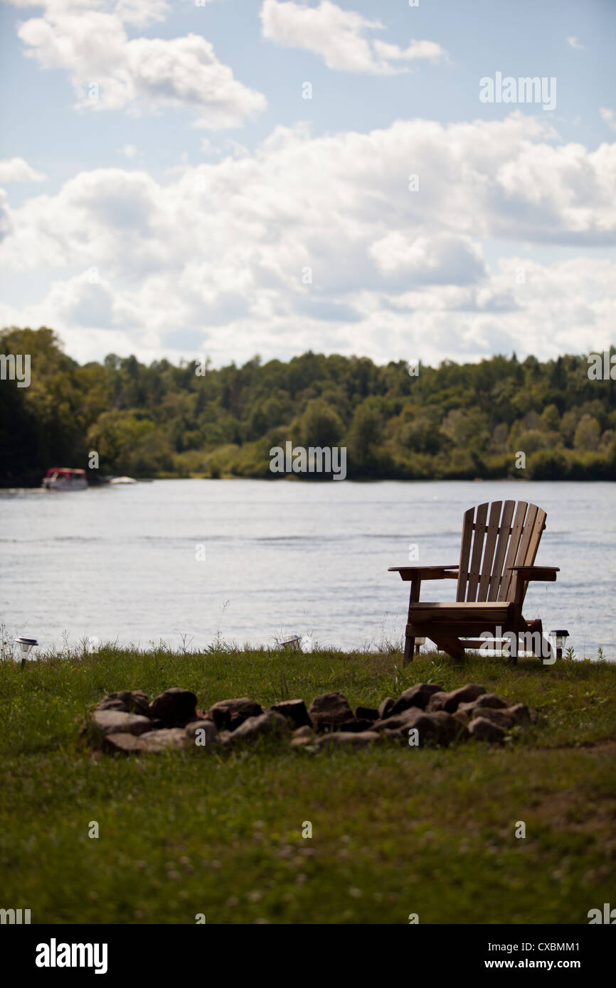 Eine Adirondack Stuhl sitzt mit einer Feuerstelle. Stockfoto