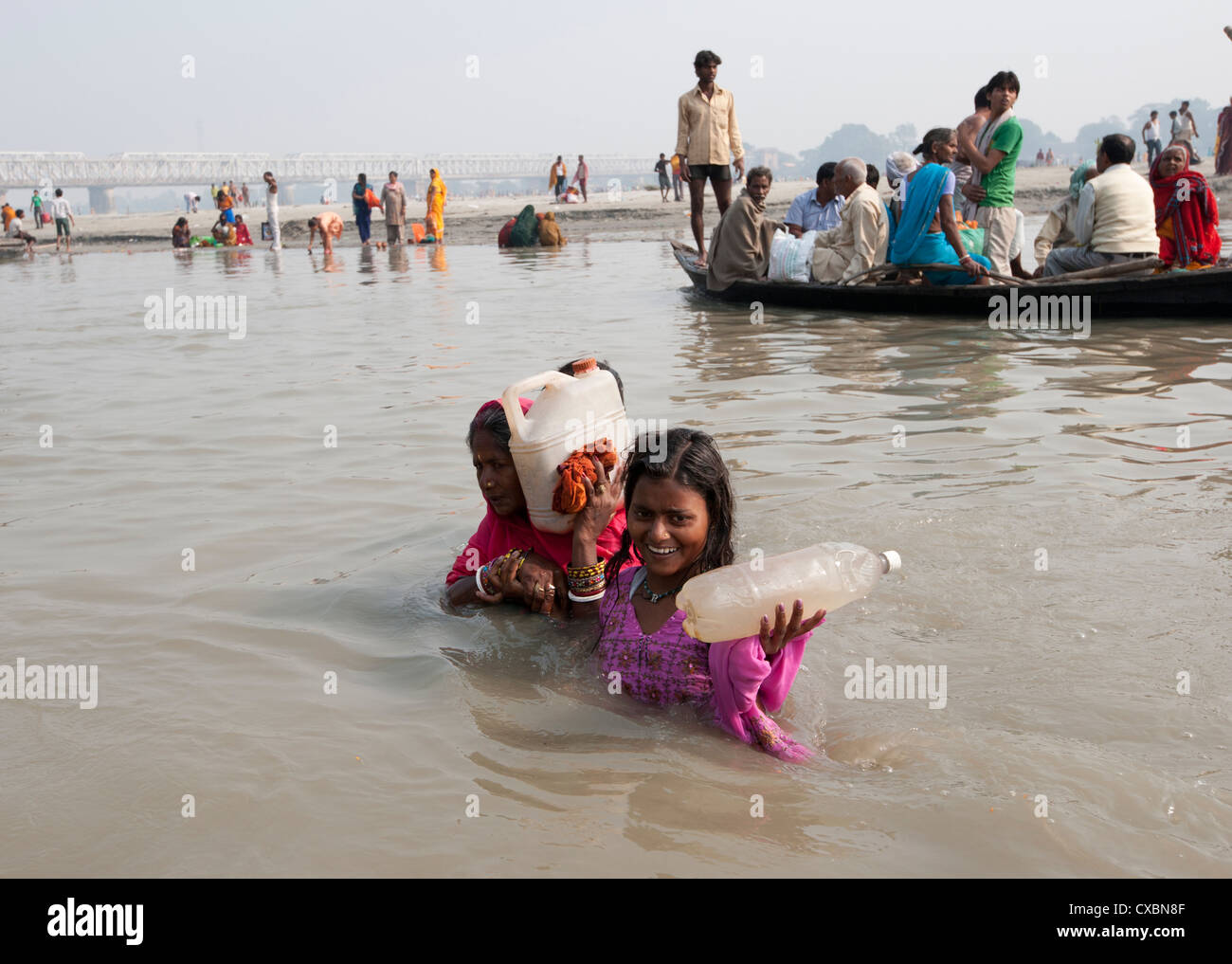 Mutter und Tochter waten über den Fluss Ganges halten Flaschen des heiligen Ganges Wasser, Sonepur, Bihar, Indien, Asien Stockfoto