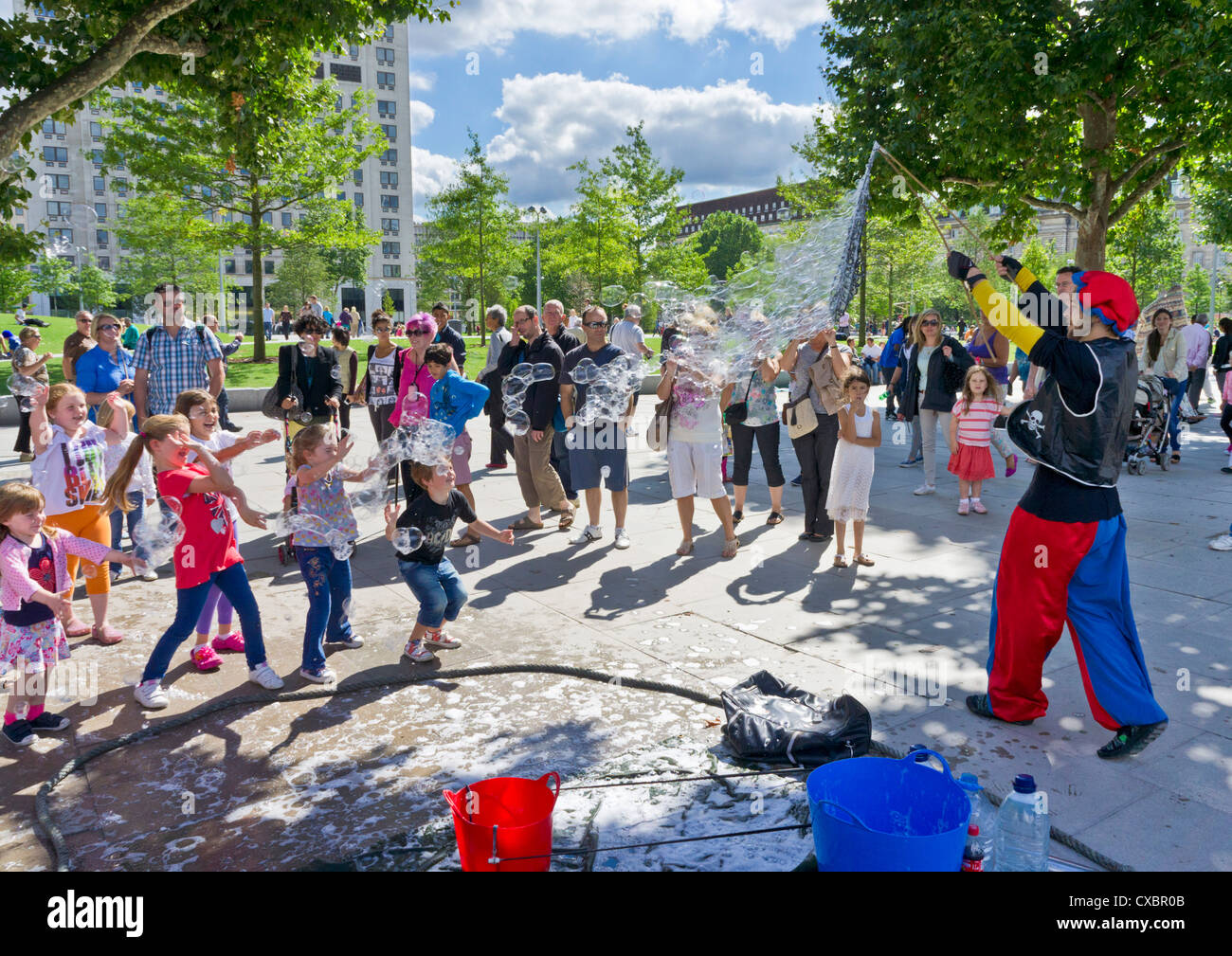 Kinder und Eltern beobachten einen Streetart-Künstler machen riesige Seifenblasen Jubilee Gardens London England UK GB EU Mitteleuropa Stockfoto