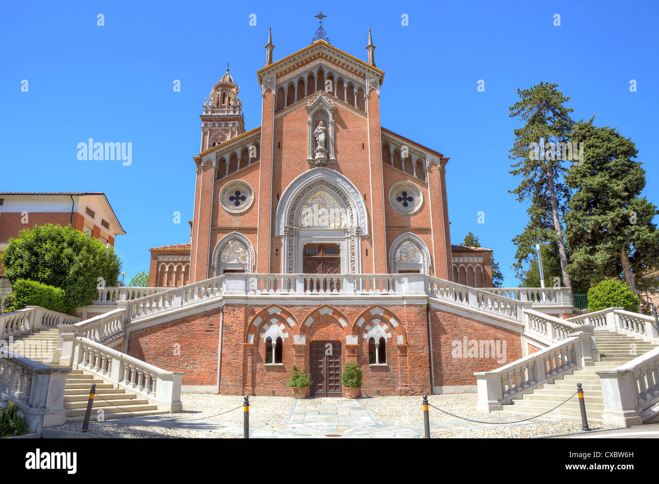 Weiße Treppe in Richtung schöne rote katholische Kirche unter blauem Himmel in Monforte D'Alba, Piemont, Norditalien. Stockfoto
