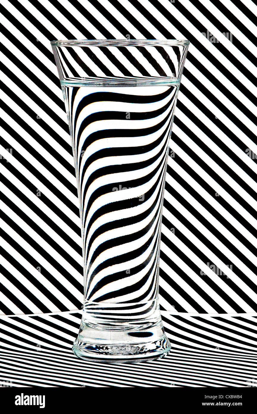 Dies ist ein Glas Wasser erschossen vor einem gestreiften Hintergrund um die Wirkung des Wassers in reflektiert Licht zu veranschaulichen. Stockfoto