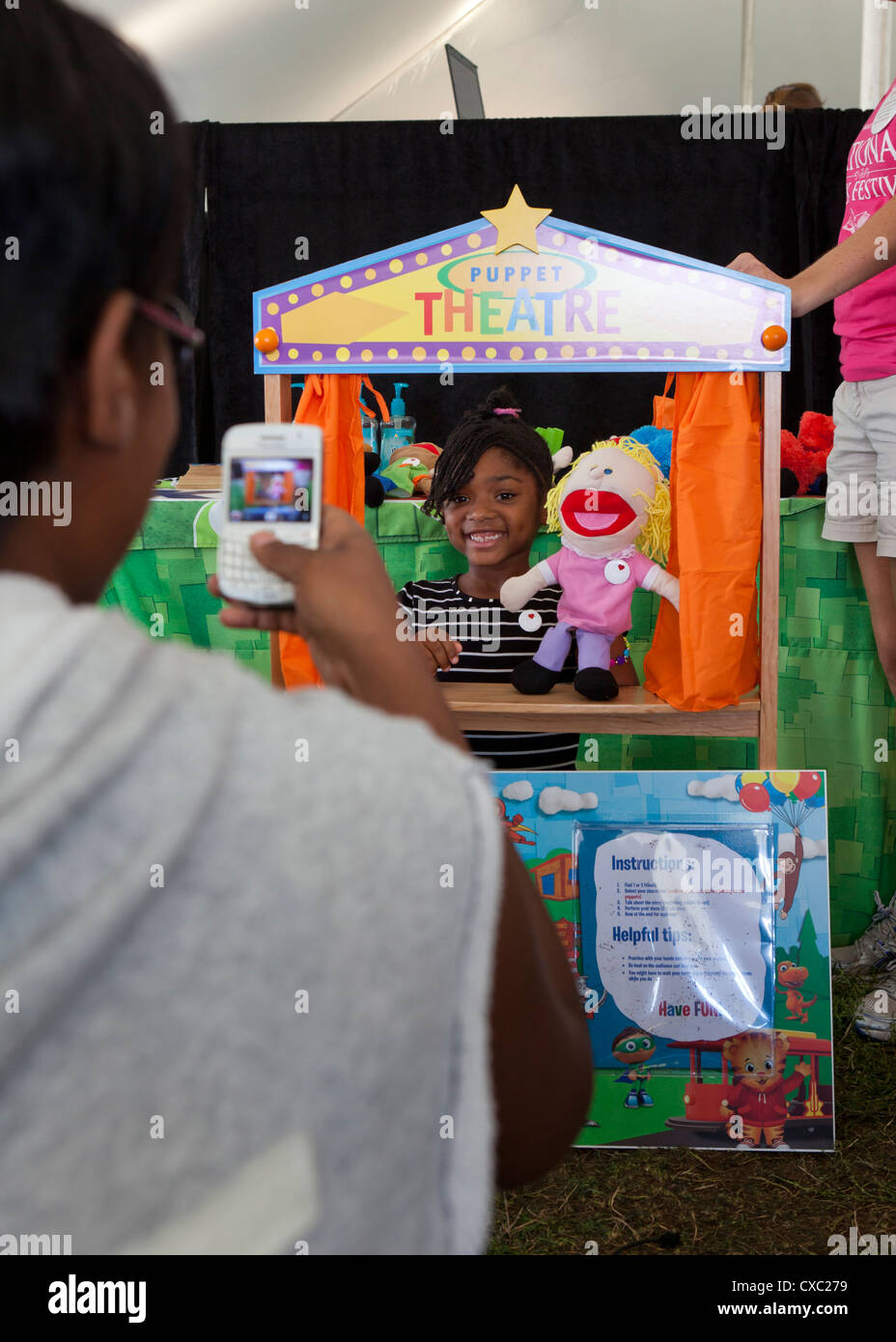 Eine afroamerikanische Mädchen posiert für Fotos hinter einer Marionette Anzeige Stockfoto