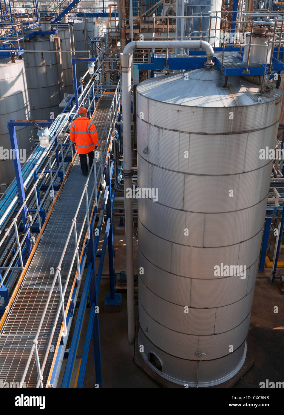 chemischen Prozess Anlagenbetreiber auf Gehweg durch Lagerung Tank Rohre Turm Strukturen Produktion Stockfoto