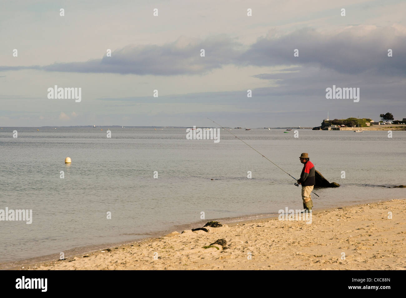 ein Mann allein Angeln am Strand von St. Pierre Quiberon, Bretagne, Frankreich Stockfoto