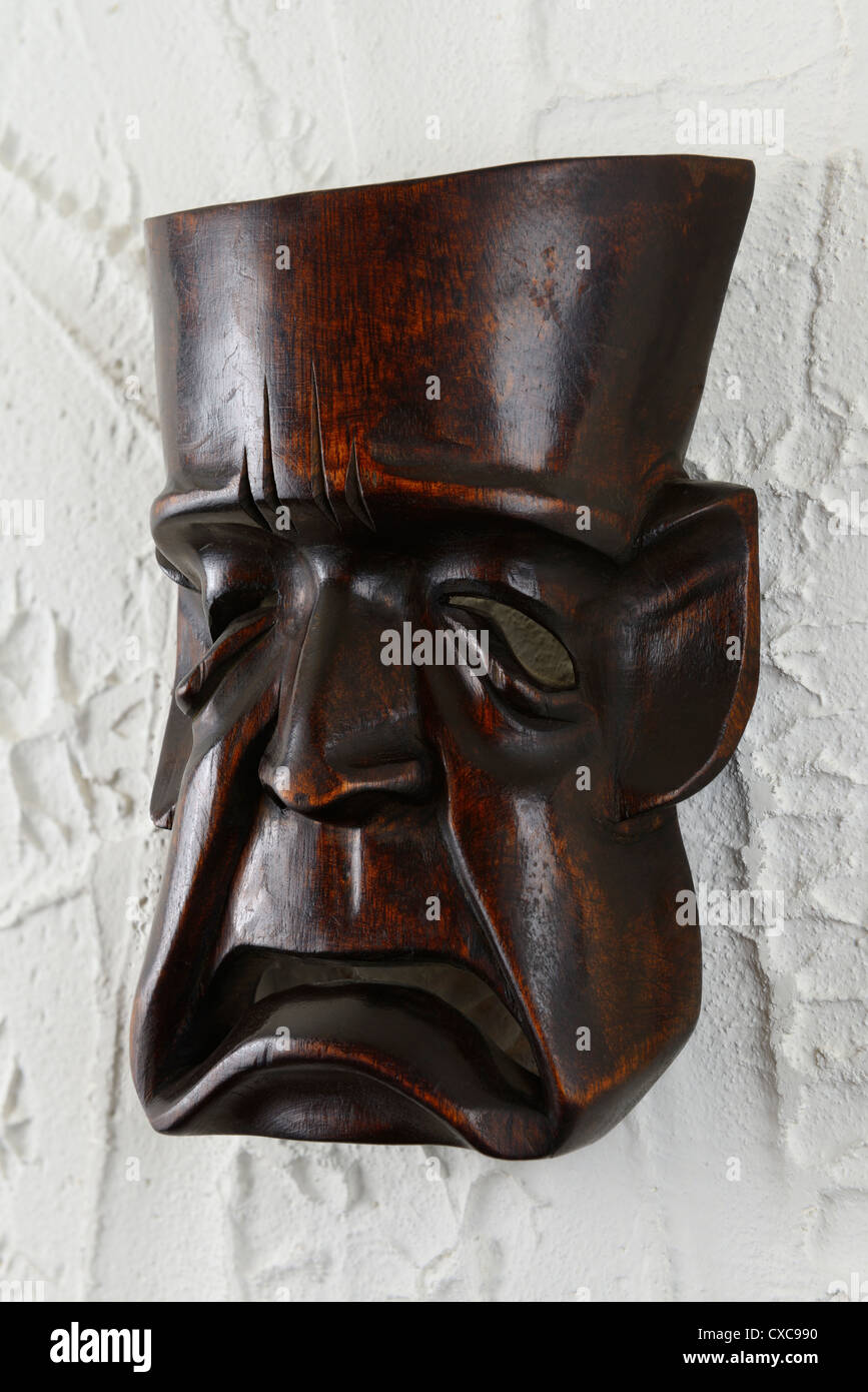 Klassische traurig weinende griechische Tragödie Holz Theater Maske an einer weiß verputzten Wand hängen Stockfoto