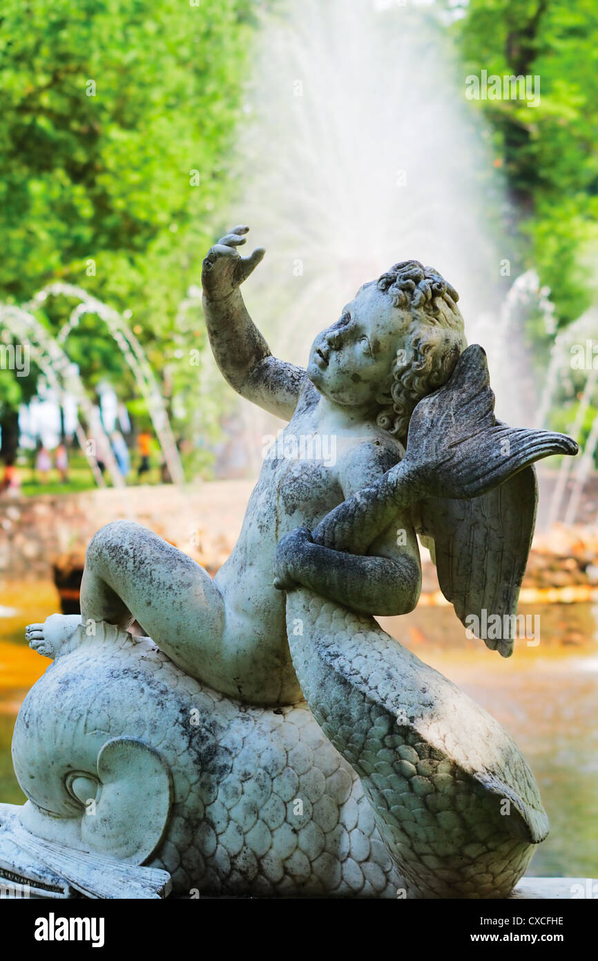 Engel reitet auf einem Delphinbrunnen auf dem Hintergrund von 'The Sun' Stockfoto