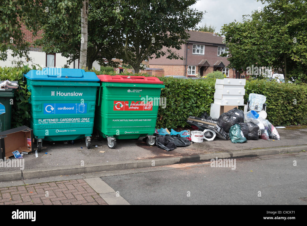 Illegale Fliege Trinkgeld neben Kunststoff und Pappe recycling Container auf eine kleine flache Entwicklung in Hounslow Middx, UK. Stockfoto