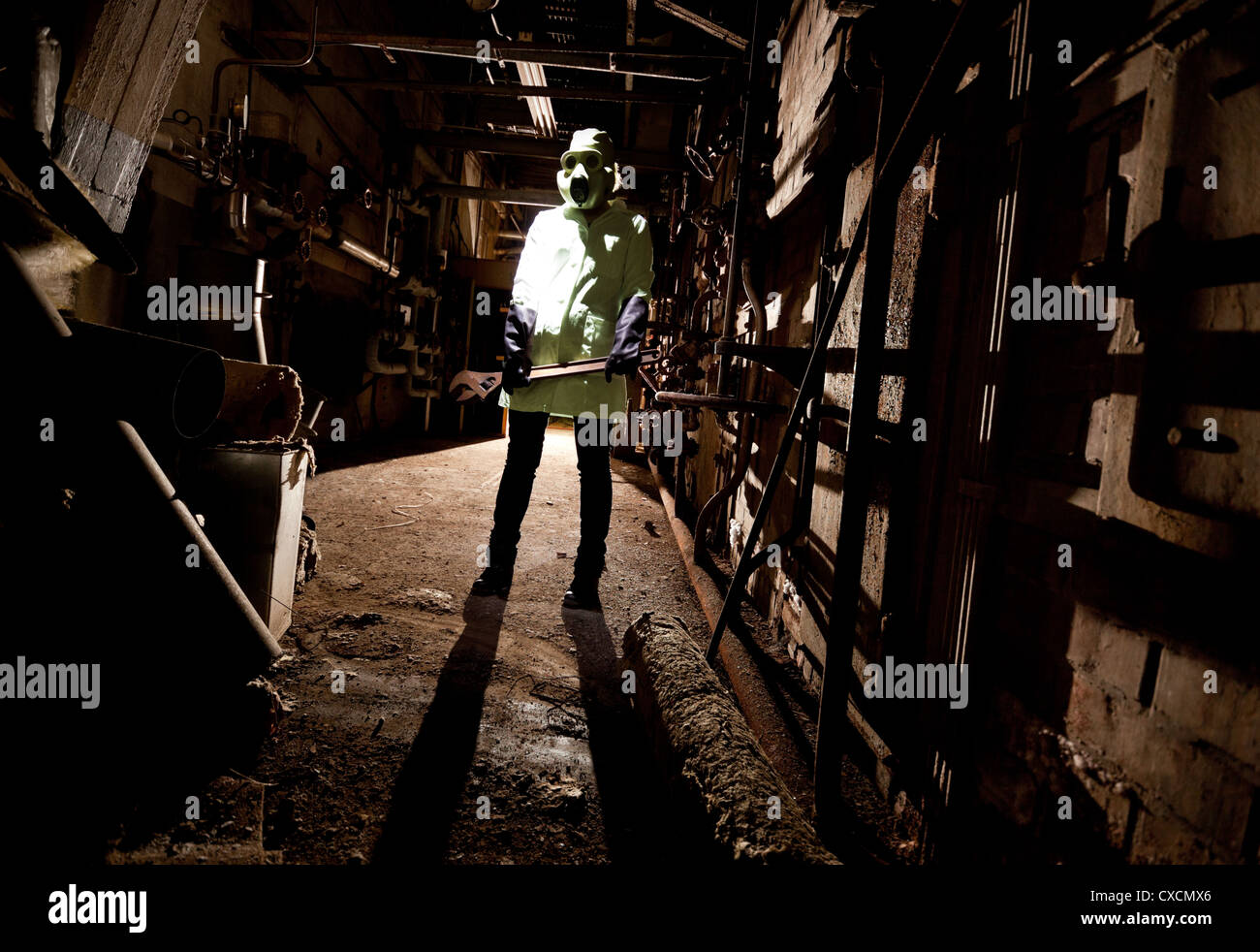 Gas maskierte Person im dunklen mit einem großen Schraubenschlüssel Stockfoto